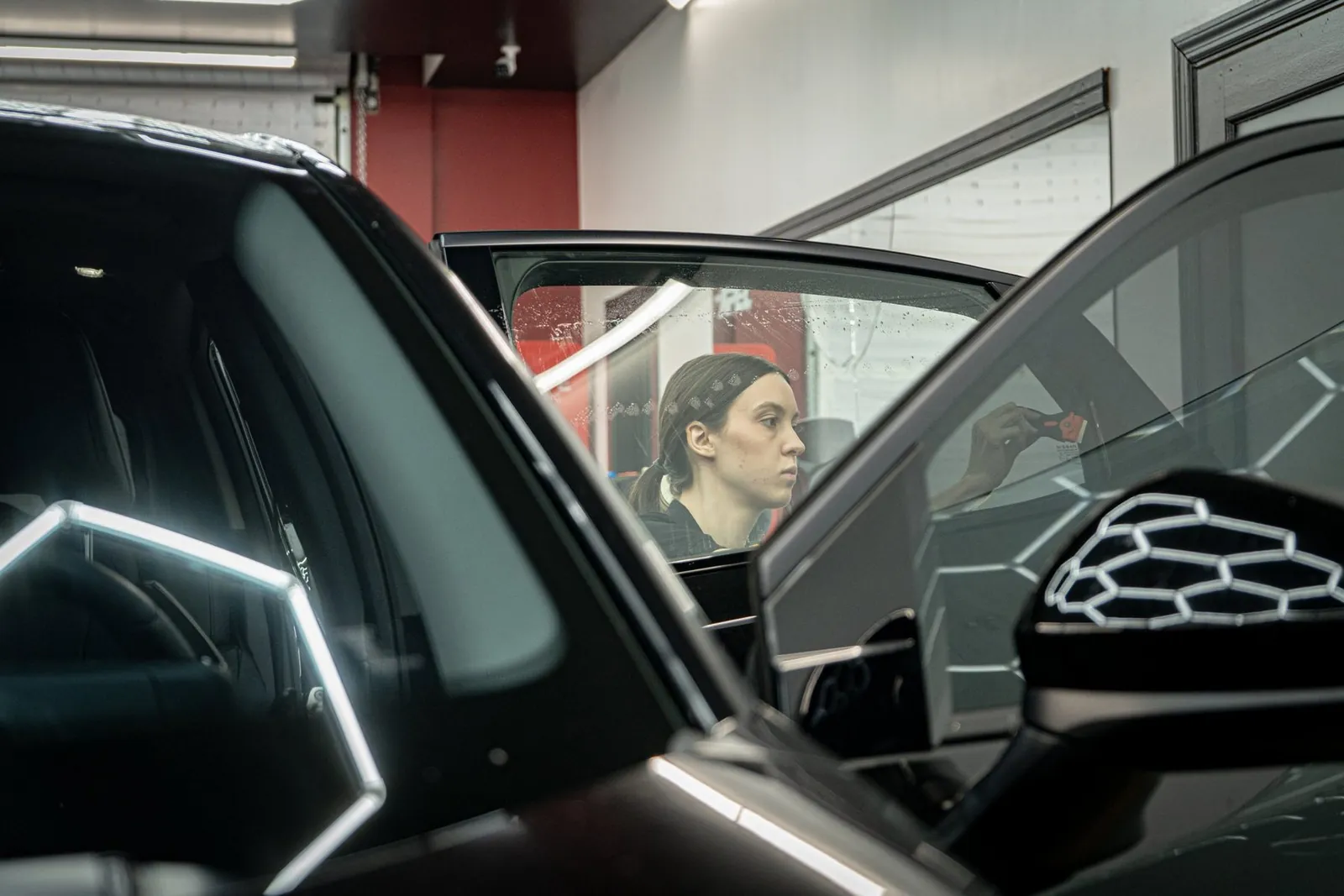 Tint technician working on a car door in our bay