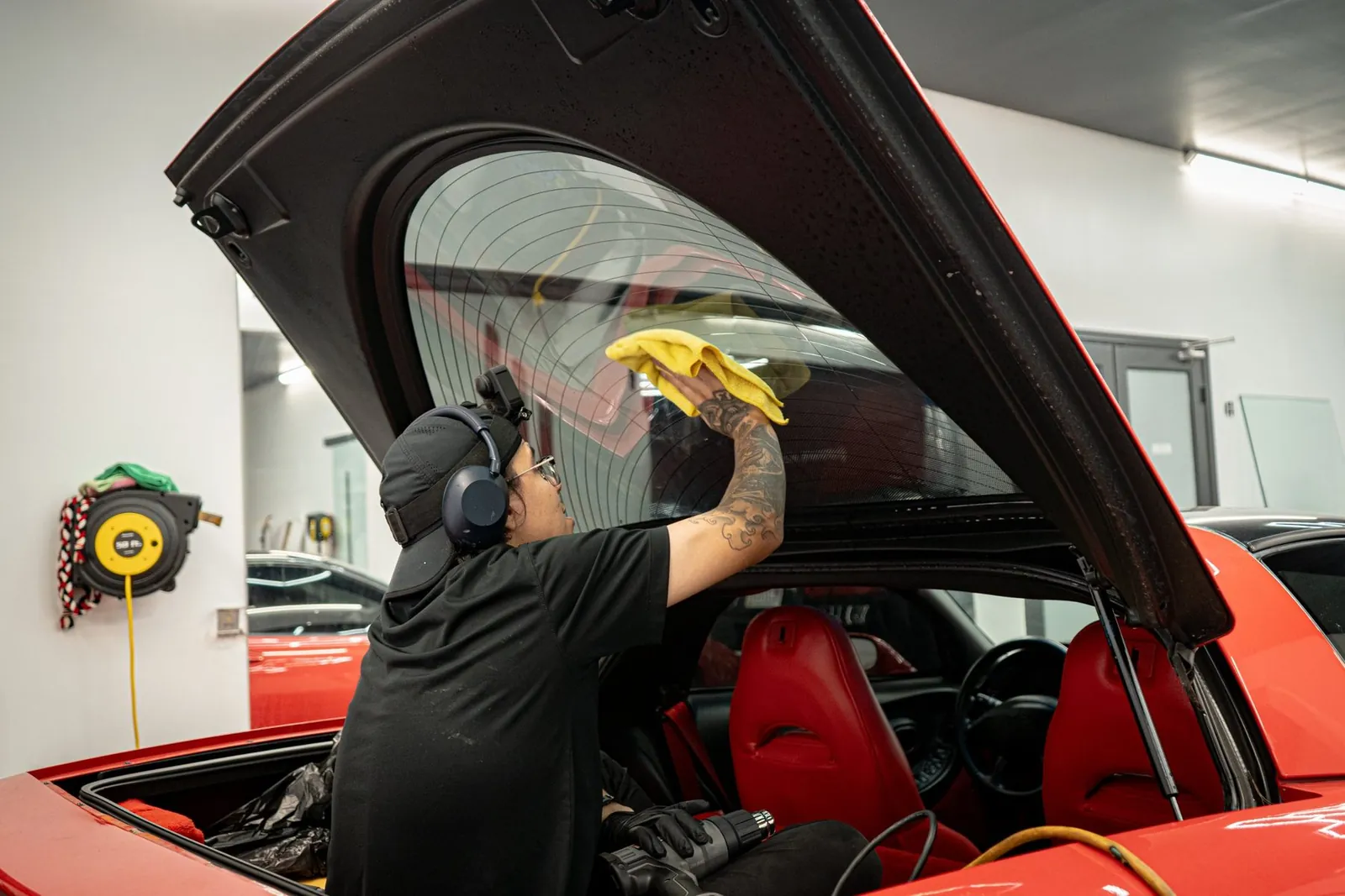 Installer prepping the rear glass of a red Corvette